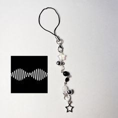 a black and white photo with a silver chain attached to an earring that has some beads hanging from it