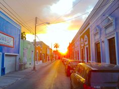 cars parked on the side of a street in front of buildings at sunset or sunrise