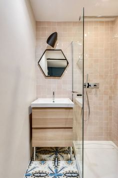 a bathroom with a sink, mirror and shower stall in the corner next to a tiled floor