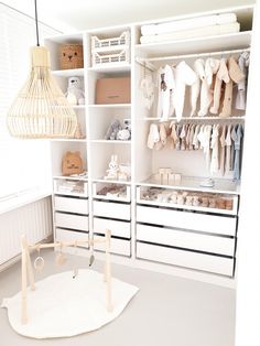 a white closet filled with lots of baby clothes and toys next to a lamp hanging from the ceiling