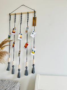 a wall hanging with pictures and tassels attached to the side of it, next to a white chair