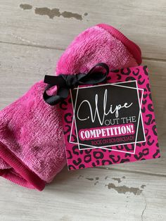 a pink mitt with a black bow on it that says wipe out the competition