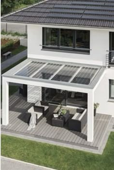 an aerial view of a white house with solar panels on the roof and patio area