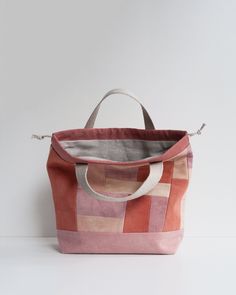 an orange and pink tote bag sitting on top of a white table next to a wall