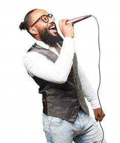 a man with a beard and glasses singing into a microphone while holding a mic in his right hand