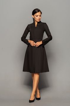 "A beautiful structured dress featuring high neck collar, a-line silhouette, and long sleeves. - high neck (stand collar) - trapeze skirt with inverted front pleat - long sleeves with elegant cuffs - knee length (midi) - a line silhouette - the dress is decorated with high-quality metal buttons Perfect as party, modest bridesmaid or elegant office dress. Seasons: autumn, winter, spring. Color: Black Fiber: viscose - 60%, elastan - 5%, polyester - 35% Concealed back zipper closure For Size S (6 U Dresses With Sleeves Elegant, Cocktail Dress Classy Evening, Elegant Purple Dresses, Formal Wedding Guest Dresses, Elegant Cocktail Dresses, Wedding Guest Dresses With Sleeves, Marsala Dress, Unique Cocktail Dresses, Stand Collar Dress