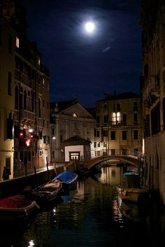 the moon is setting over some buildings and boats