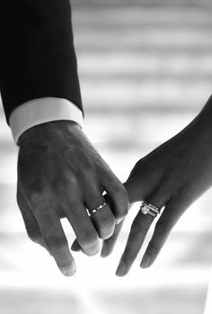 the bride and groom hold hands as they stand close to each other with their wedding rings on their fingers