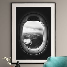 an airplane window with the view of mountains and clouds through it, framed in black and white