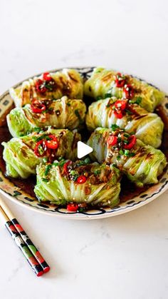 a plate filled with cabbage covered in sauce next to chopsticks