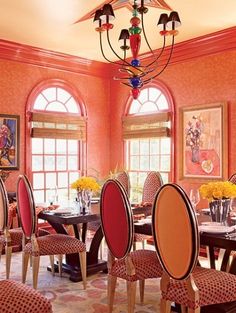 the dining room is decorated in orange and red colors with matching chairs, chandelier, and artwork on the walls