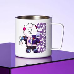 a white and purple mug with a cartoon character on it sitting on top of a table