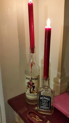 two candles are lit next to an empty bottle