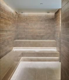 an empty bathroom with stone walls and benches in the shower area is lit by recessed lighting