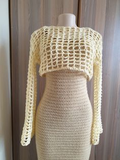 a crocheted top on a mannequin's body is shown in front of a wooden wall