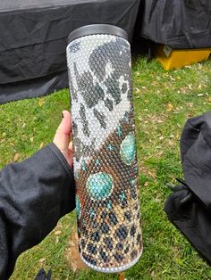 a person holding up a large vase made out of snakeskinned fabric and beads