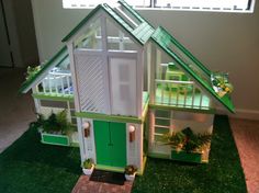 a green and white doll house on fake grass