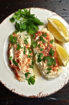 an easy baked parmesan grouper on a plate with lemons and parsley