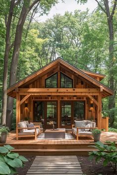 a small wooden cabin in the middle of trees and grass, with furniture on the porch