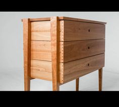 a wooden dresser with three drawers on one side and two legs at the other end