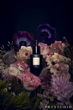 a bottle of perfume surrounded by flowers on a black background with the words, prstudi