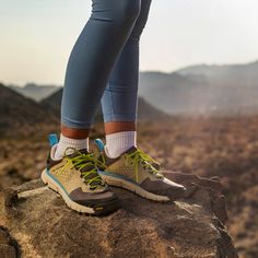 a person standing on top of a rock with their feet in the air and wearing running shoes