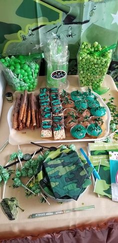 a table topped with lots of green treats and candies on top of it's trays