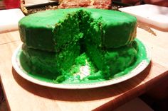 a cake with green frosting is on a plate and has one piece cut out