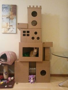 a cat sitting in a cardboard castle made to look like it is built into the floor