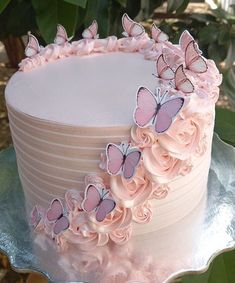 a cake with pink frosting and butterflies on top is sitting on a platter