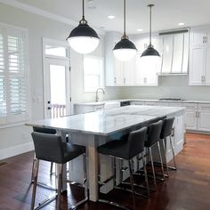 a large kitchen with white cabinets and marble counter tops, along with bar stools