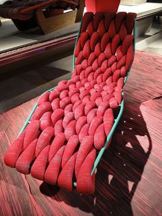 a chair made out of red cushions sitting on top of a wooden table next to a mirror