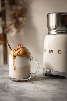 there is a cup with ice cream and caramel on it next to an espresso machine