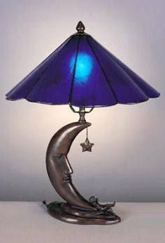 a lamp with a blue shade on top of it and a crescent moon sitting in the middle