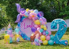 a large balloon sign in the shape of a number twenty with mermaids and balloons