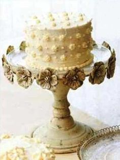 a three tiered cake with flowers on the top is sitting on a table next to plates