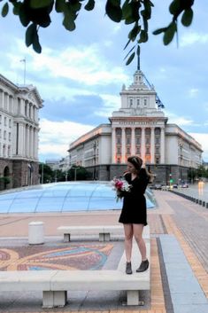 a woman standing on a bench in front of a building