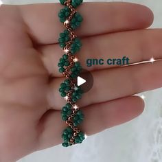 the beaded bracelet is being held in someone's hand and has green beads on it