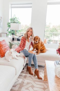 a woman sitting on top of a couch next to two dogs in a living room