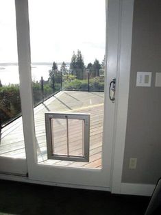 an open door with a dog looking out at the water from it's deck