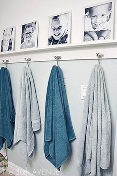 towels hanging on the wall with pictures above them and below it is a towel rack