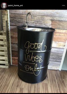 a black bucket with gold lettering on it sitting in front of a wooden paneled wall