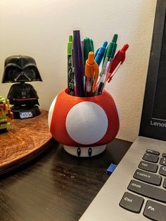 a laptop computer sitting on top of a desk next to a mushroom shaped pen holder