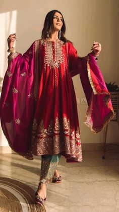 a woman in a red and gold outfit standing on a floor with her arms outstretched