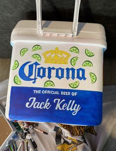 a cooler with the name corona on it sitting next to some other items in a pile