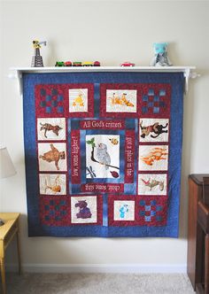 a blue and red quilt hanging on the wall next to a dresser with a lamp