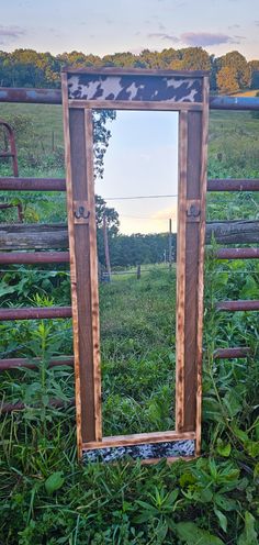 a mirror sitting on top of a wooden frame in the middle of a grass field