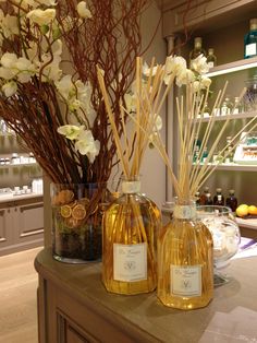 two bottles filled with liquid sitting on top of a counter next to flowers and candles