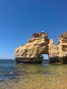 two large rocks sticking out of the ocean next to each other on a sunny day