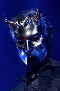 a man wearing a blue mask with horns on his head and an evil look to the side